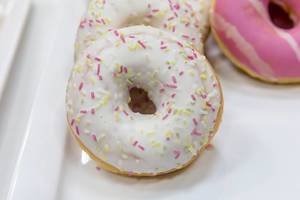 Nahaufnahme zeigt Donuts mit Zuckerguss und bunten Streuseln
