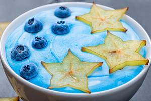 Nahaufnahmen von reifen Sternfrucht-Scheiben und Heidelbeeren mit blauem Joghurt auf Haferflocken