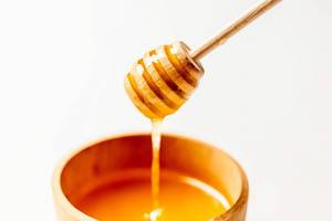 Natural bee honey in a wooden bowl on a white background