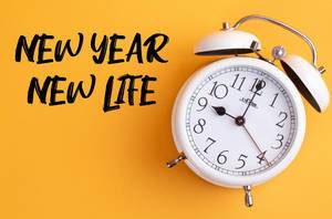 Neues Jahr: Wecker mit dem Text ‘New year, new life’ vor gelbem Hintergrund