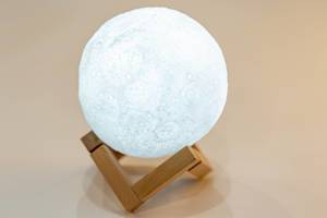 Night light in the form of a shining moon on a wooden stand