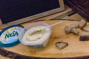 Noa - Hummus-Brotaufstrich mit 30 Prozent weniger Fett auf einer Holzplatte mit Brot