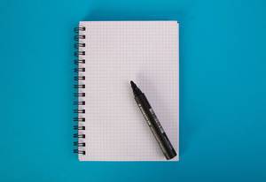 Notebook with pencil on blue background