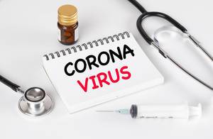 Notizbuch mit Worten Corona Virus, Medizin, Stethoskop und Spritze auf einem weißem Tisch