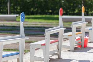 Numbered wooden chairs at a boules court