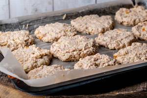 Oatmeal cookies dough with apples and dried apricots on a baking sheet before baking