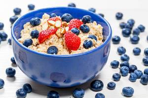 Oatmeal with fresh blueberries, almonds and strawberries in a blue bowl