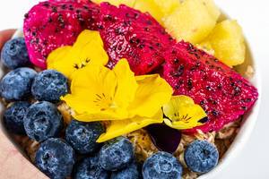 Oatmeal with fruit and flowers close-up