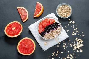 Oatmeal with grapefruit, black elderberry and sunflower seeds on a black background. Top view