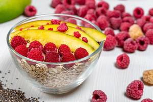 Oatmeal with mango slices, raspberries and Chia seeds in a glass bowl (Flip 2019)