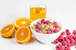 Oatmeal with raspberries, fresh oranges and a glass of juice