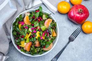 Obene Aufnahme von vegetarischem Wintersalat mit Mandarinen, Granatapfel, Paprika, Apfel und Salatblättern