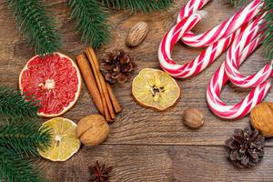 Obene Aufnahme von Weihnachtslutschern mit getrockneten Zitrusfrüchten, Zapfen und Tannenzweigen