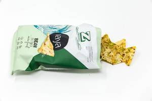 Offene Verpackung mit veganen Bohnen- und Kichererbsenchips Vaya - Salt Snack - von Zweifel, auf weißem Hintergrund