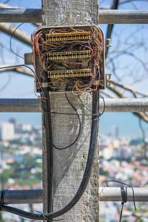 Offener Sicherungskasten mit diversen Elektrokabeln vor der Stadt Vung Tau im Hintergrund