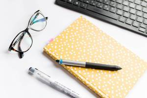 Office table with notebook, computer and reading glasses