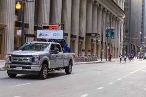 Official Chicago Marathon jeep with panel showing the current duration of the race precedes the athletes along the marathon route in LaSalle Street