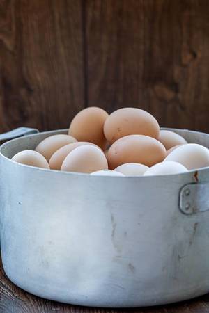 Old pan with chicken eggs on wooden background