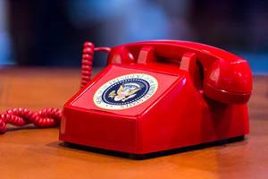 Old red vintage phone with Seal of the president of the united states as a sticker on it