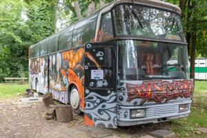 Old retro bus full of graffities with BaseCamp sign in the front at the BaseCamp youth hostel in Bonn
