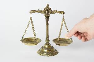 Old-School Golden scale in balance with a hand putting a coin on it