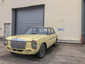 Oldtimer car Mercedes 200D in light yellow stands in front of garage entrance