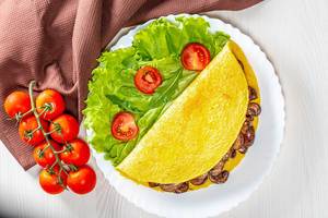 Omelet stuffed with fried mushrooms with fresh lettuce and tomatoes (Flip 2019)