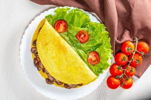 Omelet stuffed with fried mushrooms with fresh lettuce and tomatoes