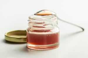Open small jar of strawberry jammed with a spoon