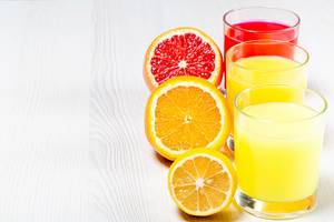 Orange, lemon and grapefruit fresh juices on a white wooden background