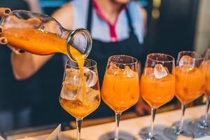 Orange-Mango Cocktail wird in Gläser gegossen