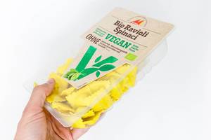 Organic, vegan and lactose-free: hand holds a package of Bio Ravioli with spinach by Mosna on a white background