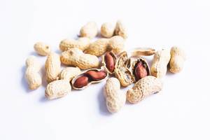 Organic whole in-shell peanuts on white background