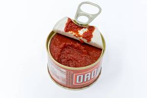 Oro tomato paste in an opened small can on white background