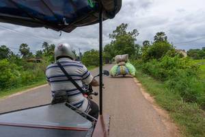 Overloaded Motorbike driving in front of a TukTuk in Siem Reap