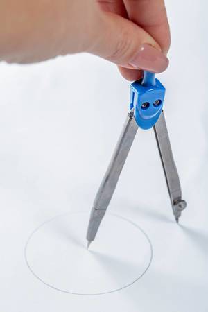 pair of compasses drawing circle on a paper