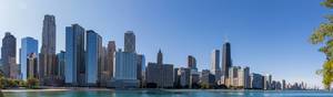 Panoramic image of the Chicago skyline with skyscrapers by the water with blue sky and no clouds