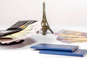 Passports, open wallet with cards and money and the Eiffel tower on white background