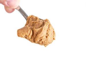 Peanut Butter on the spoon above white background