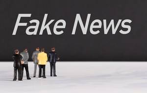 People standing in front of Fake News text