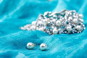 Perlenohrringe und Kette auf einem blauen Tuch