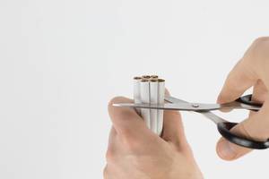 Person Cutting a Bunch of Cigarettes with Scissors to Quit Smoking on White Background