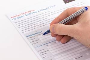 Person füllt ein Antragsformular für Verbraucherkredit Bericht mit einem Kugelschreiber aus