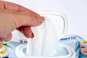 Person taking white wet tissue out of packaging