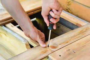 Person using Screwdriver to attach Wooden Bar to DIY Construction