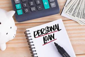 Personal loan text in notebook with piggy bank and calculator on wooden table