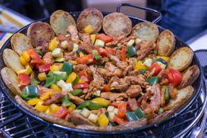 Pfanne mit Kartoffelscheiben, Fleischstücken und buntem Gemüse auf raucharmem Lotusgrill