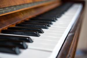 Piano keys close up diagonal view of a dark brown and wooden piano