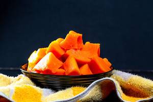 Pieces of baked pumpkin in a black bowl with a kitchen towel