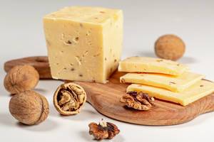 Pieces of cheese with walnuts on wooden kitchen Board